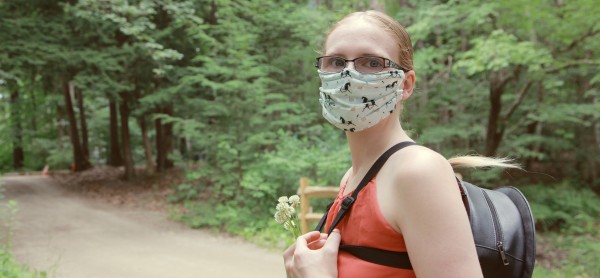 Person in a woodland wearing a mask over their mouth and nose