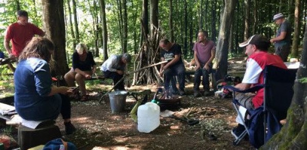 People sitting together in woodland doing woodland crafts