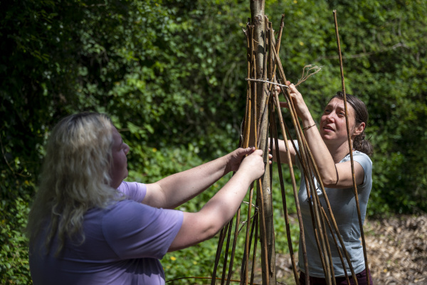 Two people building a willow structure