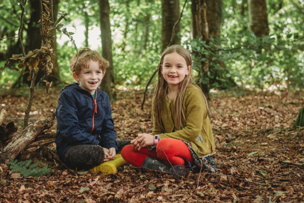 Two children smiling in a woodland during the summer