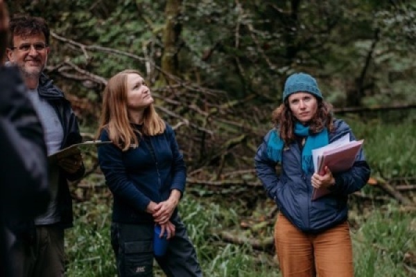 Three people in a woodland holding clipboards 